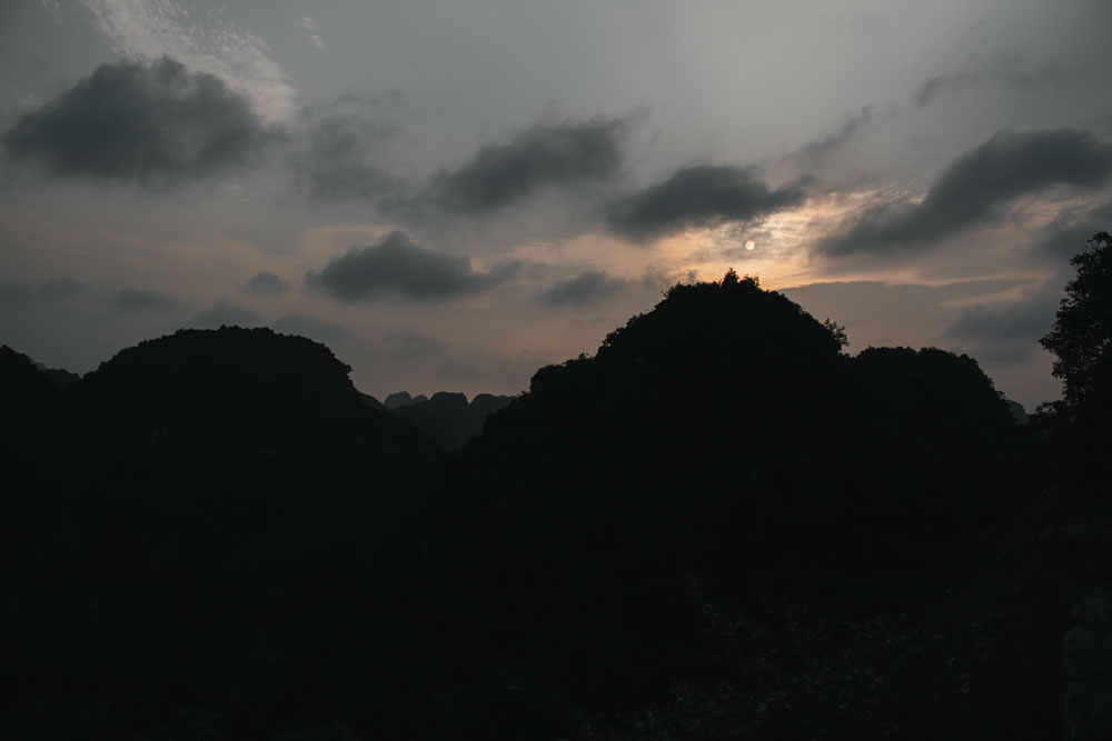 Die-Sonne-geht-beim-Mua-Cave-hinter-den-Gipfeln-unter